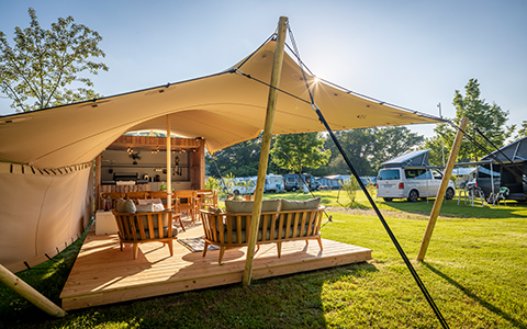 Une terrasse couverte avec un salon sur un terrain de camping.