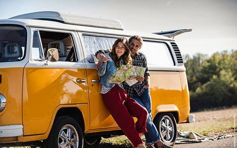Ein rosaroter VW Bus fährt auf einem Campingplatz.