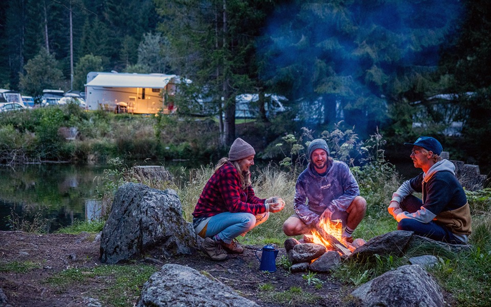 Un camping près d'une rivière au coucher du soleil.