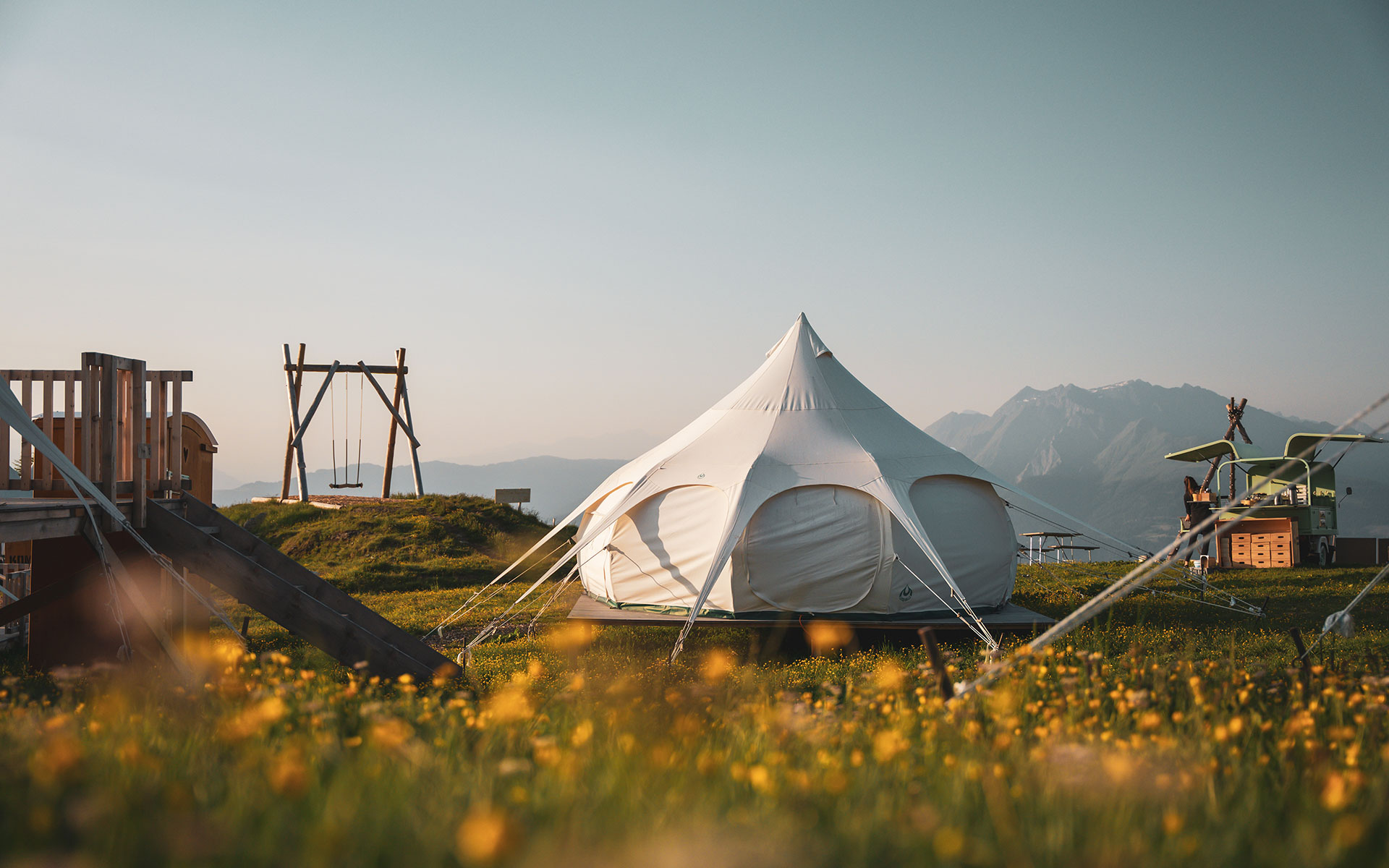 Una tenda rotonda su un alpeggio con vista sulle montagne.